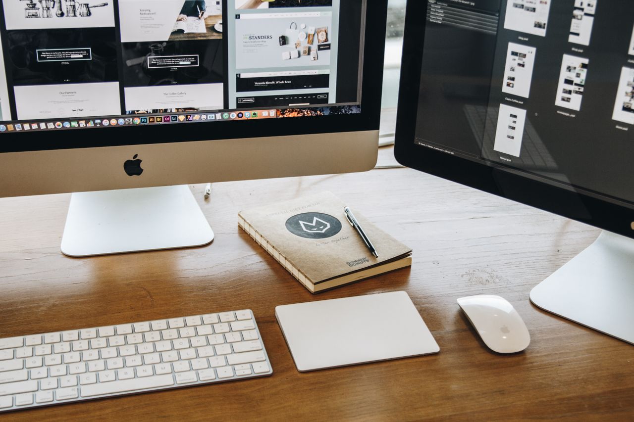 Un bureau épuré avec deux écrans, un clavier, une souris et un carnet, pensé pour la productivité.